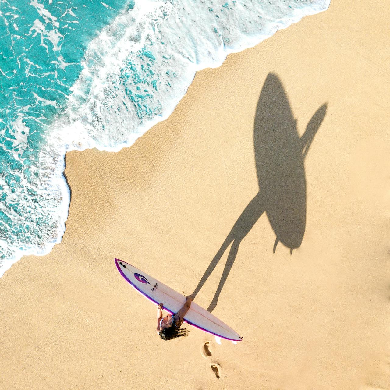 a sufer in a beach, top view, shadows