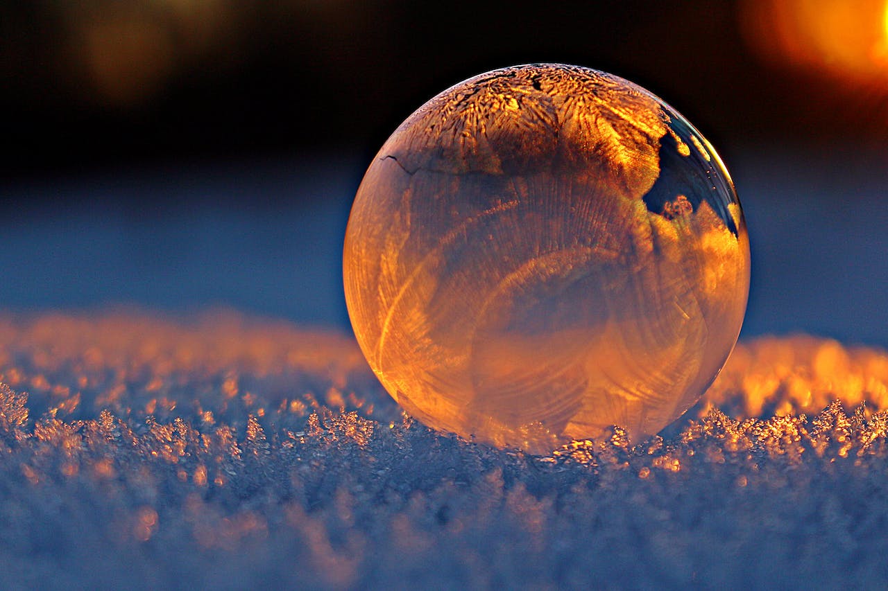 a frozen bubble on top of some snow, illuminated with a warm light from the back