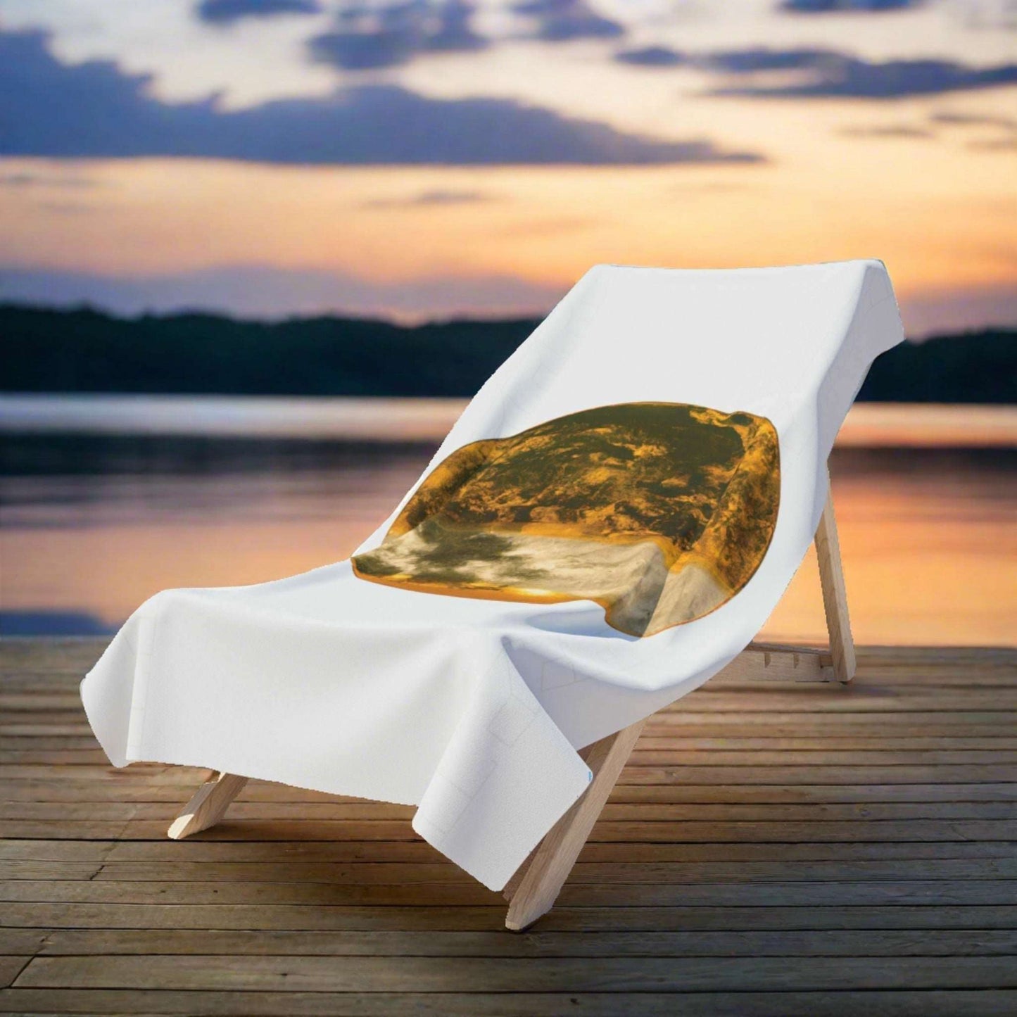 As evening falls, the Gilded Twilight Collection bath towel 36"x72" lies on a wooden deckchair by a tranquil lakeside. The last rays of the sun cast a golden glow over the scene, mirroring the towel’s warm hues. The water and sky provide a serene backdrop of deepening blues and greens, highlighting the towel's rich design