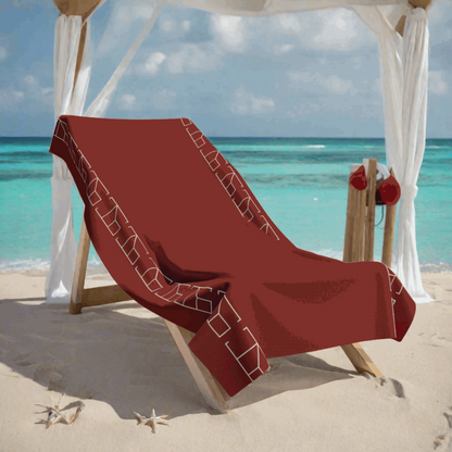 Bath Towel Burnt Umber Red in prestigious beach club scene where the red beach towel is displayed on a deluxe cabana bed with white curtains gently blowing in the sea breeze. The cabana is set on a white sandy beach with crystal-clear turquoise waters in the background. The scene is accessorized with silver and white decorative elements that give a chic and upscale contrast to the towel's vivid red.