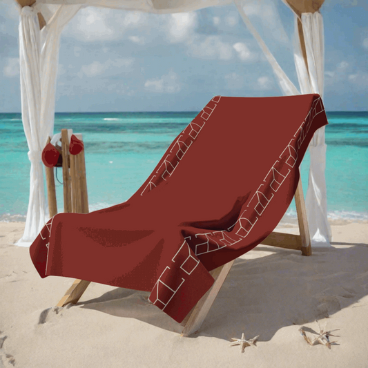 Bath Towel Burnt Umber Red in prestigious beach club scene where the red beach towel is displayed on a deluxe cabana bed with white curtains gently blowing in the sea breeze. The cabana is set on a white sandy beach with crystal-clear turquoise waters in the background. The scene is accessorized with silver and white decorative elements that give a chic and upscale contrast to the towel's vivid red.